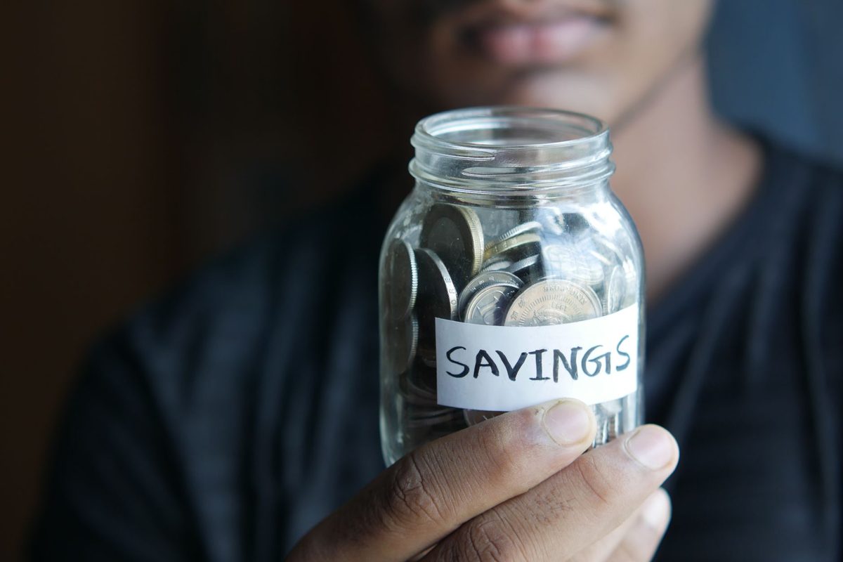 A glass jar of coins labeled for retirement savings, representing the choice between a Roth IRA and a taxable brokerage account