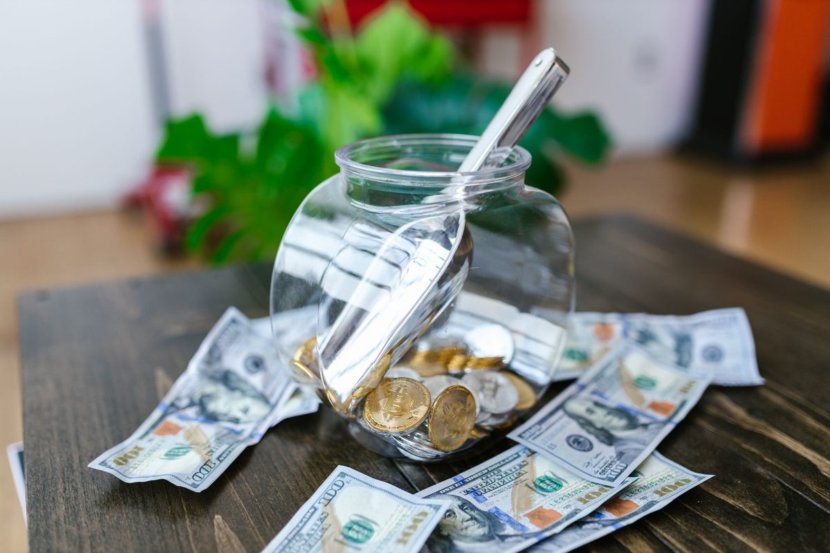 A glass savings jar filled with coins and dollar bills, illustrating short-term bonds vs high-yield savings accounts