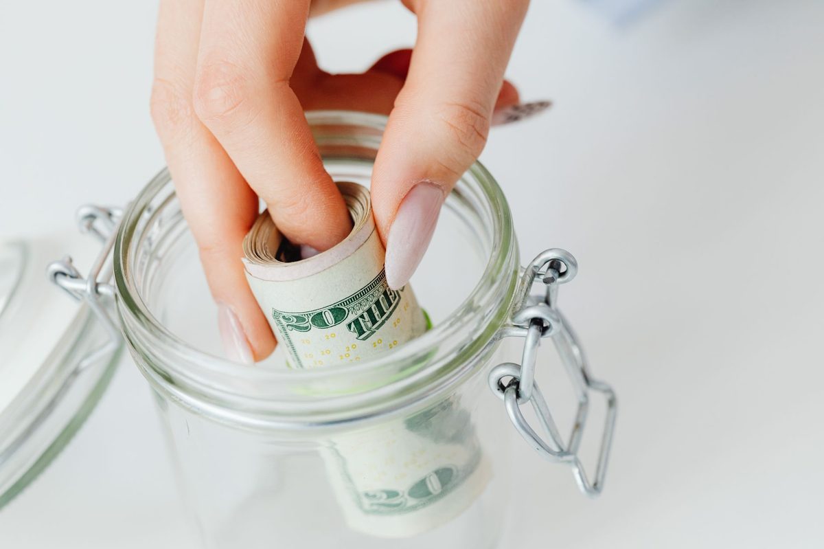 Emergency fund savings jar with cash and dollar bills