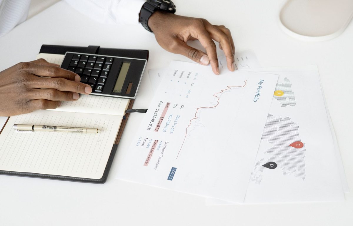 Investment portfolio on laptop screen with tax calculator and year-end planning notes